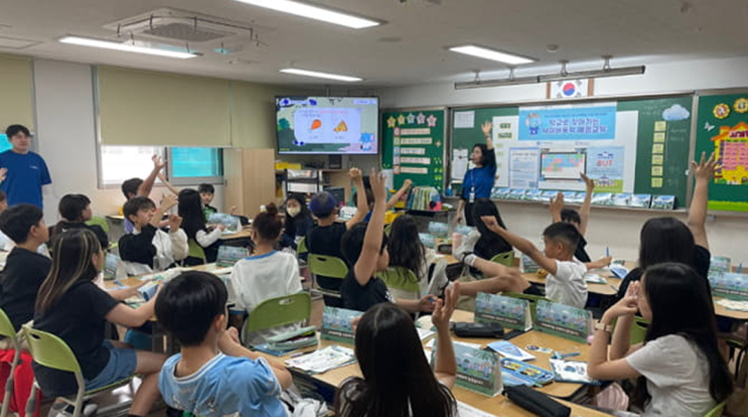 초등학교 교실에서 디지털 교육 수업에 참여하며 손을 든 학생들의 모습